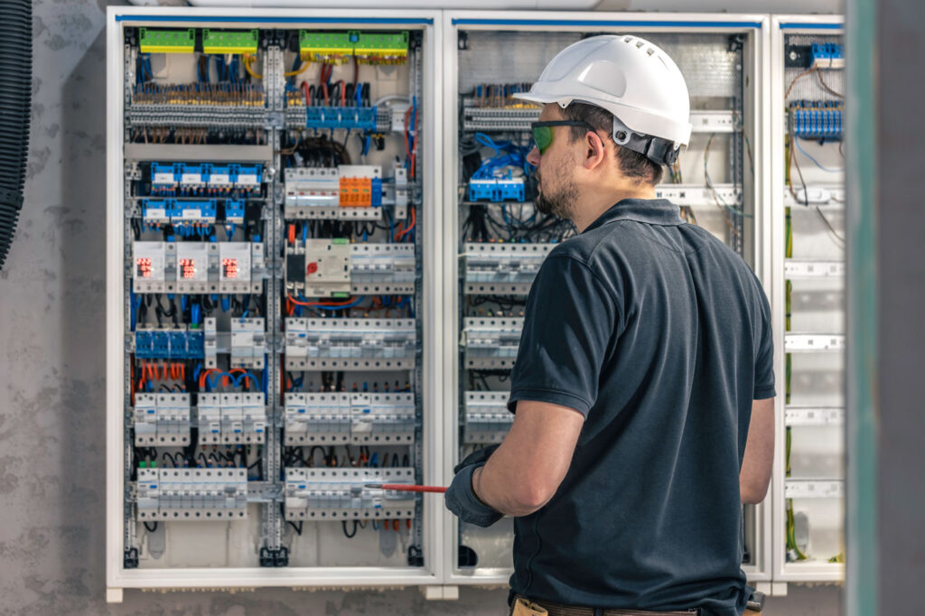 a-male-electrician-works-in-a-switchboard-using-an-2024-03-21-15-16-06-utc2